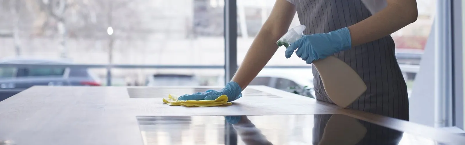 a person cleaning a countertop wearing gloves