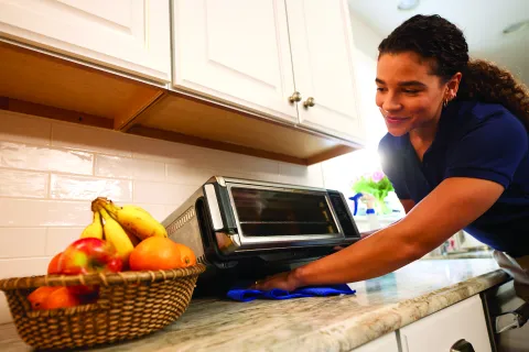 a person cleaning under toaster oven