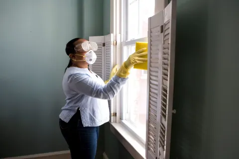 a person wearing a mask cleaning a window