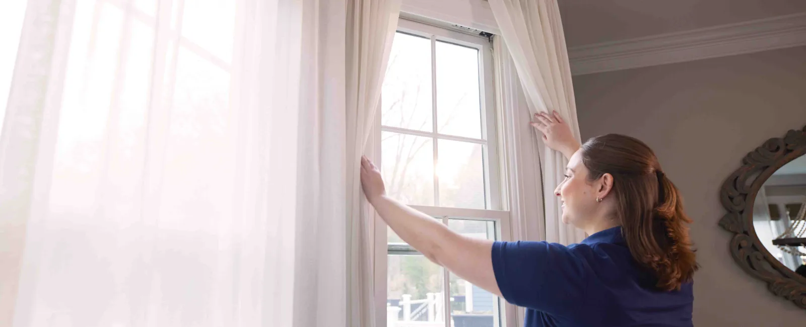 a person in a blue shirt opening curtains