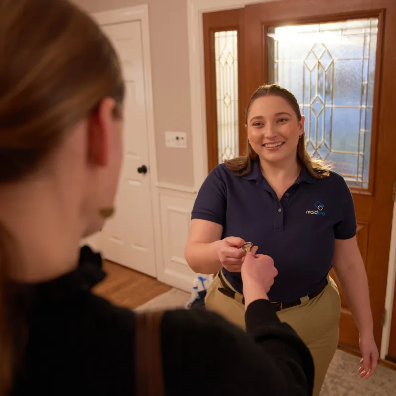 a woman in a blue shirt receiving a key from a homeowner while smiling